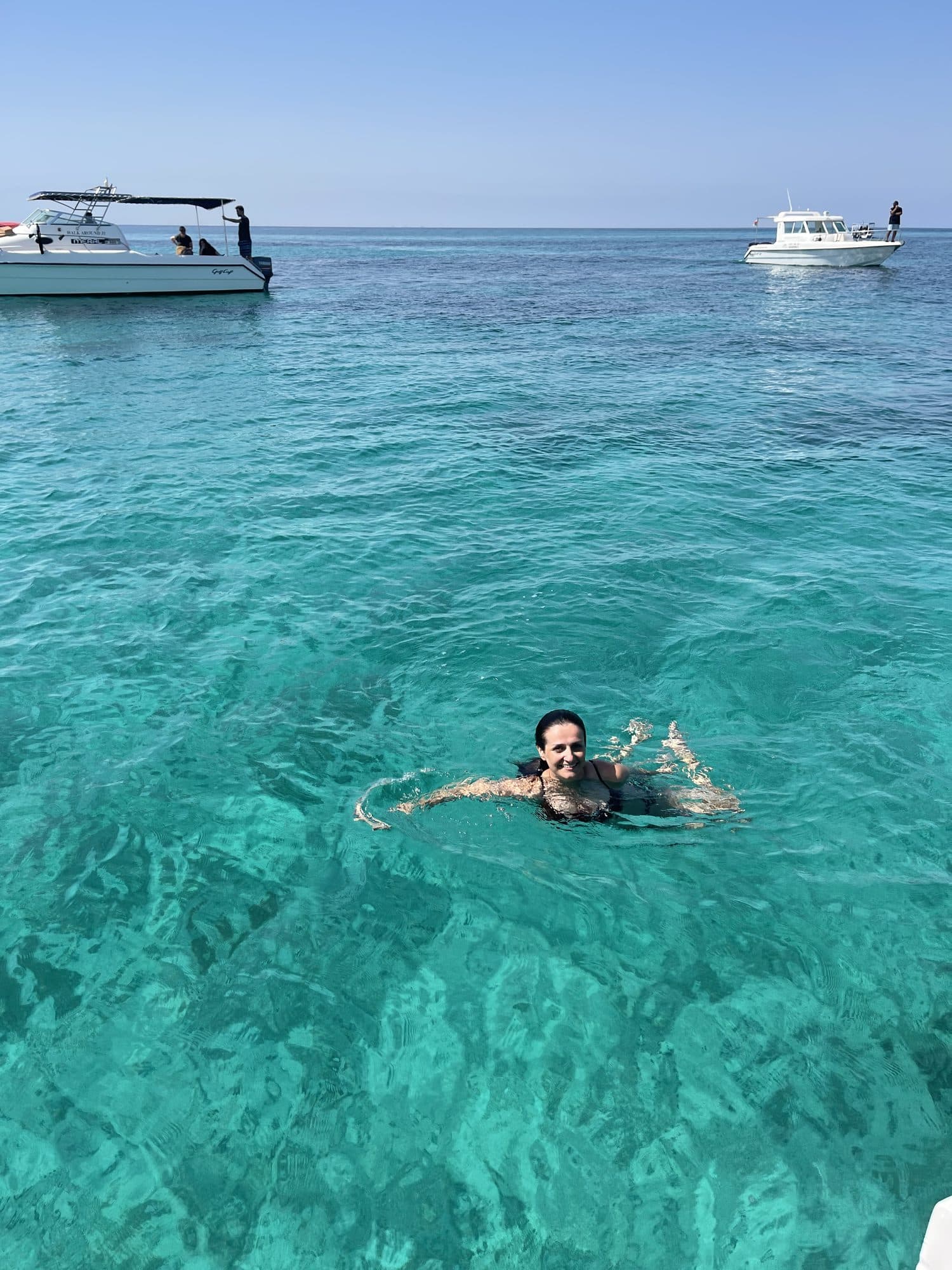 A snorkeller in the clear turquoise water beside the boat at the Daymaniyat Islands